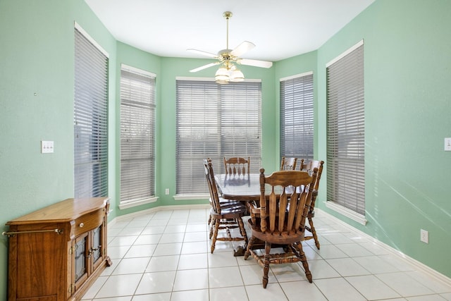 dining area with light tile patterned flooring, a ceiling fan, and baseboards