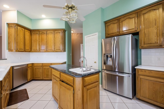 kitchen with light tile patterned floors, appliances with stainless steel finishes, brown cabinetry, and a sink