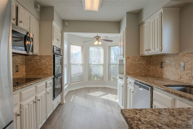 kitchen with a textured ceiling, ceiling fan, wood finished floors, light stone countertops, and black appliances