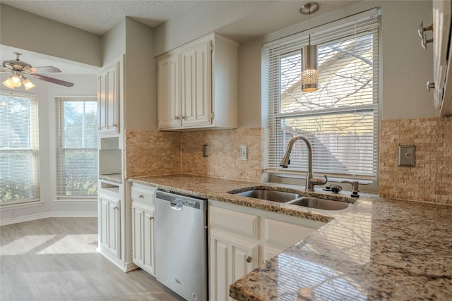 kitchen featuring backsplash, a sink, a textured ceiling, light stone countertops, and dishwasher