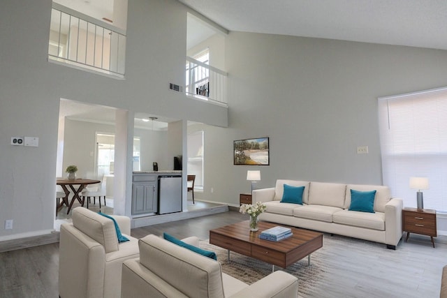 living area featuring visible vents, baseboards, wood finished floors, and beamed ceiling