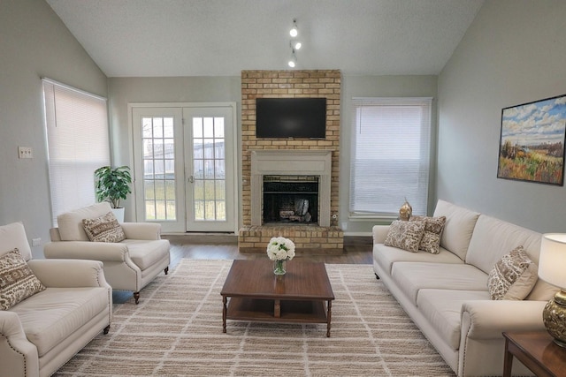 living area featuring a textured ceiling, a fireplace, vaulted ceiling, and wood finished floors