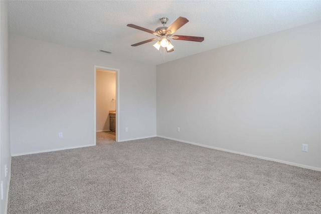 carpeted spare room featuring a textured ceiling, baseboards, visible vents, and a ceiling fan