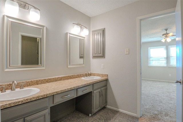 bathroom with double vanity, a textured ceiling, baseboards, and a sink