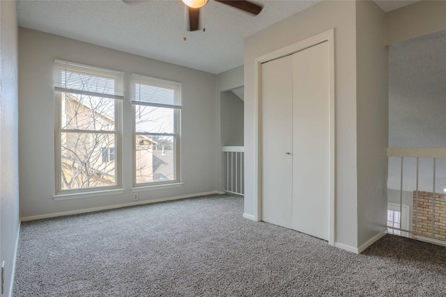 unfurnished bedroom with a textured ceiling, ceiling fan, carpet flooring, baseboards, and a closet