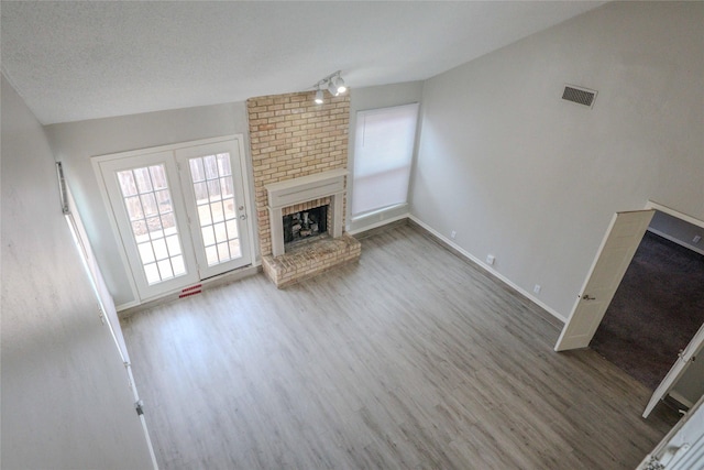 unfurnished living room with visible vents, a fireplace, baseboards, and wood finished floors