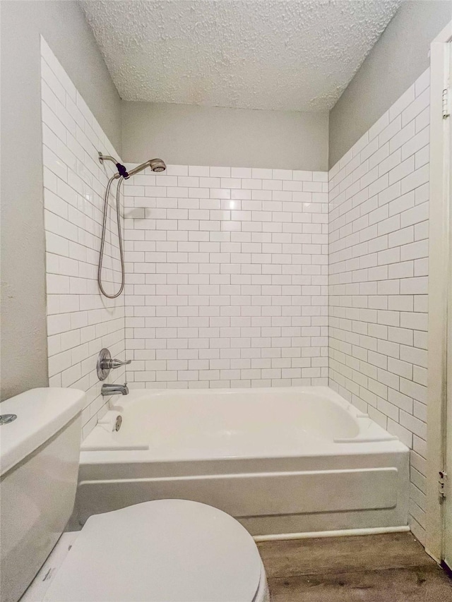 full bathroom with a textured ceiling, bathing tub / shower combination, and toilet