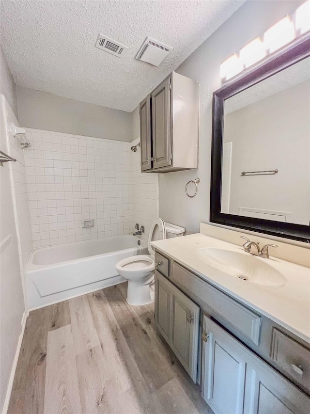 full bath with toilet, wood finished floors, vanity, bathing tub / shower combination, and visible vents