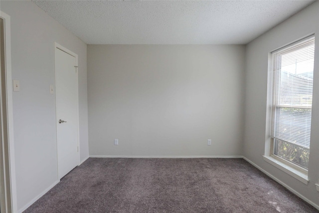 carpeted spare room with plenty of natural light, baseboards, and a textured ceiling