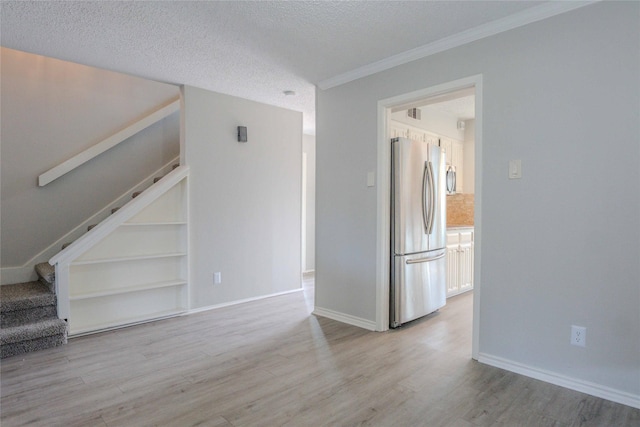 empty room featuring baseboards, stairway, a textured ceiling, and wood finished floors