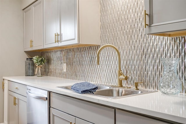 kitchen featuring light countertops, stainless steel dishwasher, backsplash, and a sink