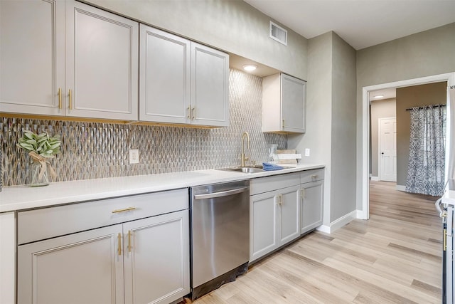 kitchen with light countertops, light wood-style flooring, decorative backsplash, a sink, and dishwasher