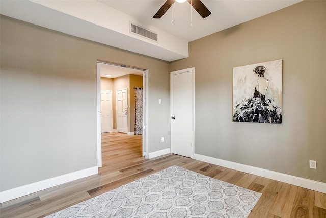 interior space with ceiling fan, wood finished floors, visible vents, and baseboards