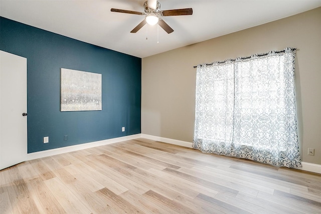 unfurnished room with wood finished floors, a ceiling fan, and baseboards