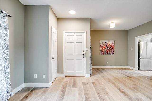 foyer with light wood-style flooring and baseboards