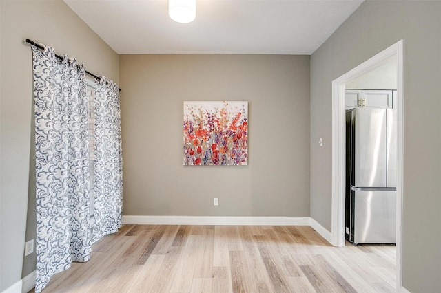 spare room featuring light wood-style floors and baseboards