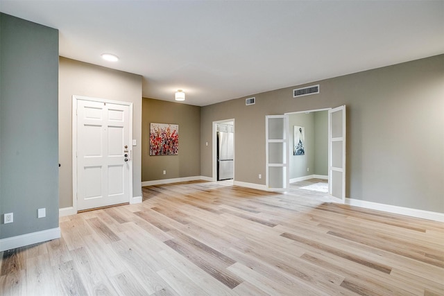 empty room featuring light wood-style floors, baseboards, and visible vents