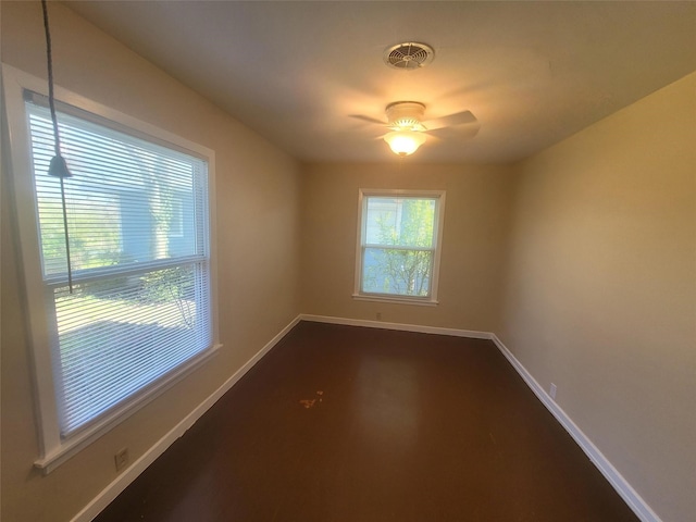 empty room featuring ceiling fan, visible vents, and baseboards