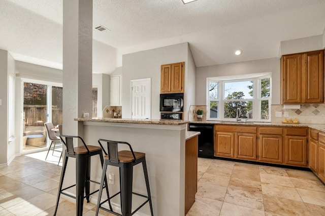 kitchen with lofted ceiling, backsplash, a sink, black appliances, and a kitchen bar