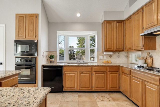 kitchen with decorative backsplash, a sink, black appliances, and light stone countertops