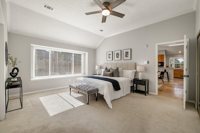 bedroom featuring visible vents, light colored carpet, ornamental molding, vaulted ceiling, and a textured ceiling