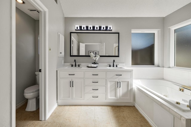 bathroom with tile patterned flooring, a sink, a jetted tub, and toilet