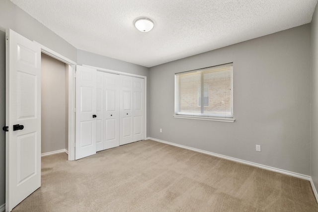 unfurnished bedroom featuring carpet, a textured ceiling, baseboards, and a closet