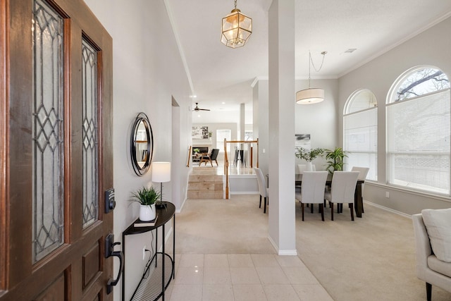 entryway featuring baseboards, light colored carpet, a healthy amount of sunlight, and crown molding