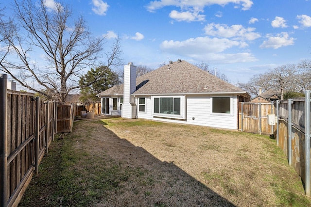 rear view of property with a yard, a chimney, a fenced backyard, and roof with shingles