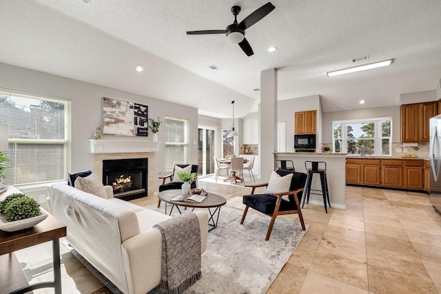 living area featuring lofted ceiling, a fireplace, visible vents, and recessed lighting