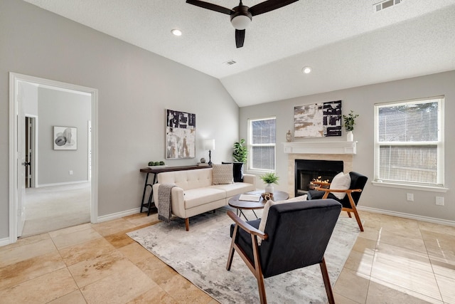 living room featuring lofted ceiling, a lit fireplace, baseboards, and a textured ceiling