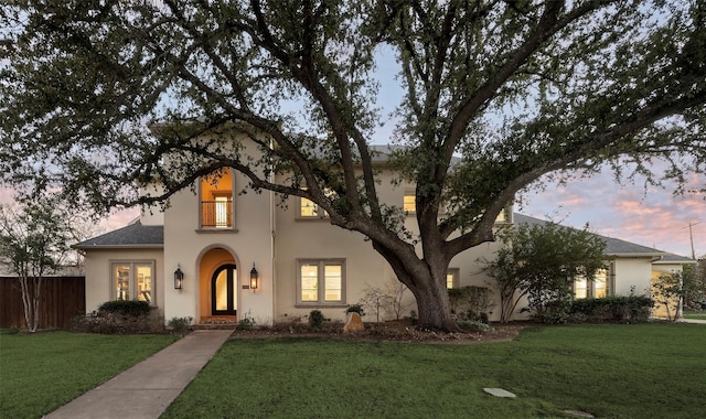 view of front of home featuring stucco siding, a yard, and fence