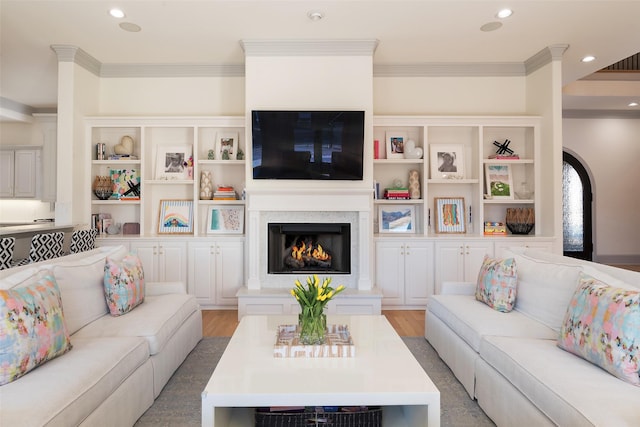 living area featuring a warm lit fireplace, ornamental molding, wood finished floors, and recessed lighting