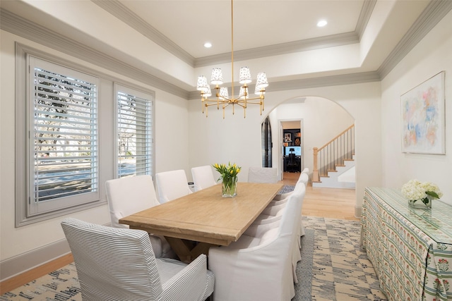dining space featuring light wood-type flooring, arched walkways, a chandelier, and crown molding