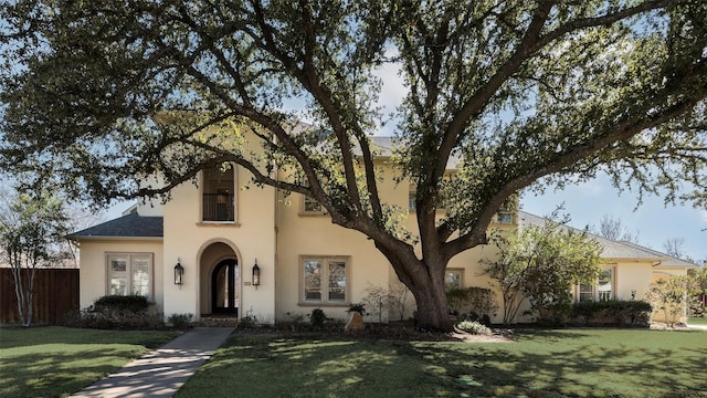 view of front of house featuring a front lawn, fence, and stucco siding