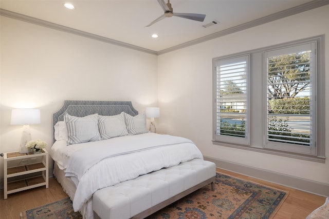 bedroom with ornamental molding, wood finished floors, visible vents, and baseboards