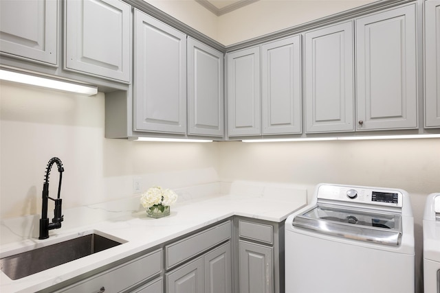 clothes washing area with cabinet space, a sink, and independent washer and dryer