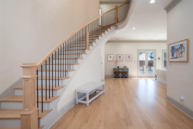 stairs featuring baseboards, wood finished floors, crown molding, french doors, and recessed lighting