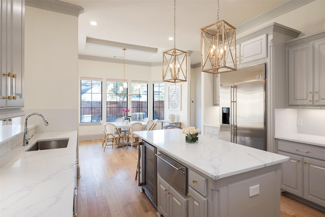 kitchen with a center island, crown molding, gray cabinetry, a sink, and built in refrigerator
