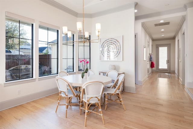 dining room featuring ornamental molding, a notable chandelier, light wood-style flooring, and baseboards