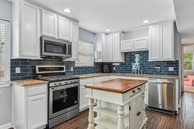 kitchen with stainless steel appliances, dark wood-type flooring, and white cabinetry