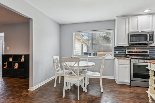 kitchen with baseboards, stainless steel appliances, dark wood-style flooring, and decorative backsplash