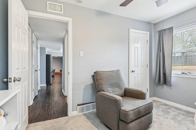 sitting room with ceiling fan, carpet flooring, visible vents, and baseboards