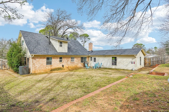 rear view of house with central AC unit, a lawn, fence, and brick siding