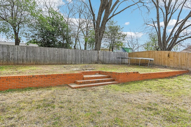 view of yard featuring a fenced backyard and a trampoline