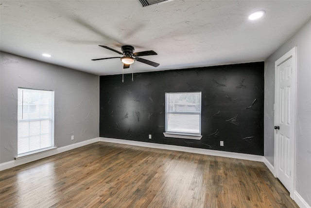 spare room featuring baseboards, ceiling fan, wood finished floors, and a healthy amount of sunlight