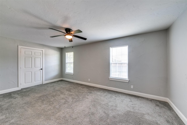 carpeted spare room featuring a ceiling fan, a textured ceiling, and baseboards