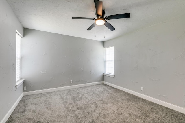 carpeted spare room featuring baseboards and a ceiling fan