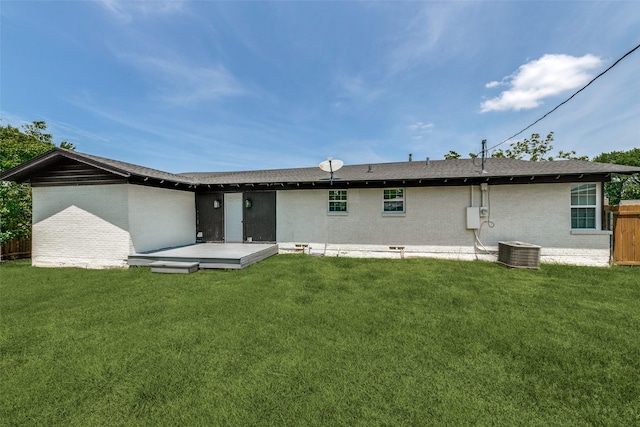 back of house featuring central AC, fence, a lawn, and brick siding