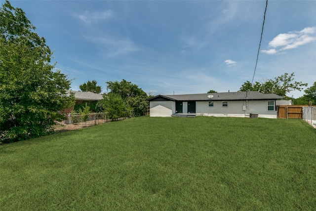 back of house with a lawn and a fenced backyard